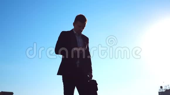 年轻的商人带着一个公文包把在西装口袋里在蓝蓝的天空中漫步视频的预览图