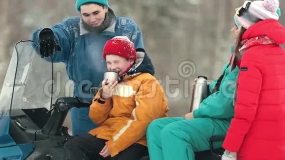 一家人坐在雪地摩托上在森林里喝茶视频的预览图