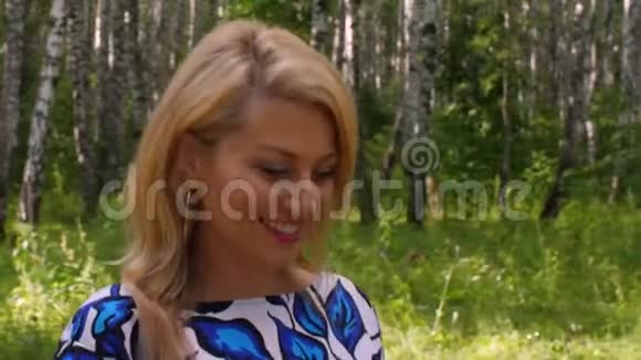 夏日在绿色公园的白桦林背景上散步的快乐女人视频的预览图