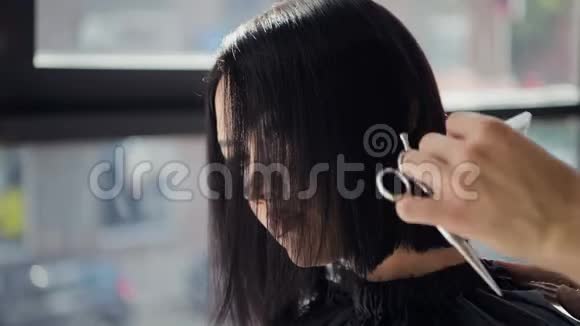 理发师用剪刀特写在沙龙里剪客户头发使用梳子视频的预览图