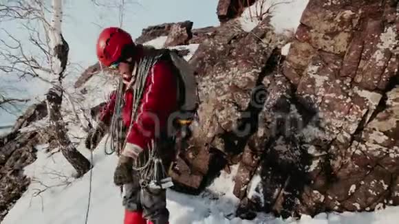 在山坡上一个穿着红色夹克和眼镜的登山者从一堆绳索上滚下来视频的预览图
