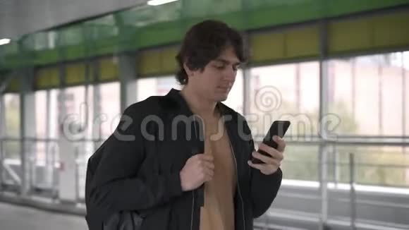 穿着黑色夹克的男人在隧道里走着一边拿起智能手机一边说话视频的预览图