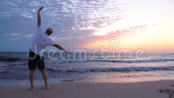 成熟的运动员在日出时在海上晨练视频的预览图