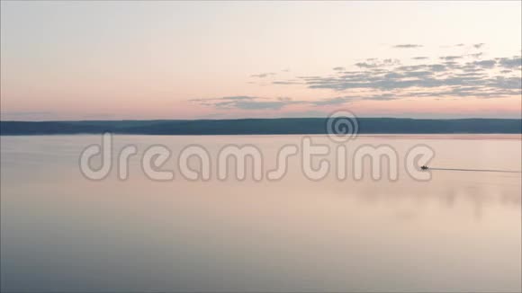 黎明时分摩托艇从高处俯瞰早晨的风景从高处看一艘孤独的小船漂浮在粉红色的水里视频的预览图