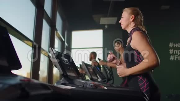 一群人跑在跑步机上靠近一个大的全景窗口集体有氧运动视频的预览图
