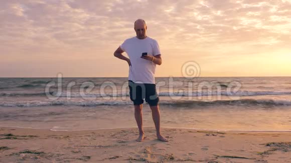 早上在美丽的海滨打电话的成年男子视频的预览图