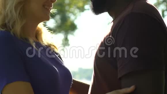 年轻的多种族夫妇在公园里微笑拥抱浪漫的约会侧视视频的预览图