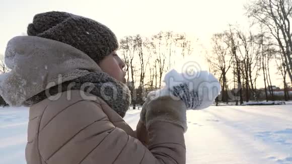 在寒冷的冬天年轻美丽的女孩在手里吹雪视频的预览图