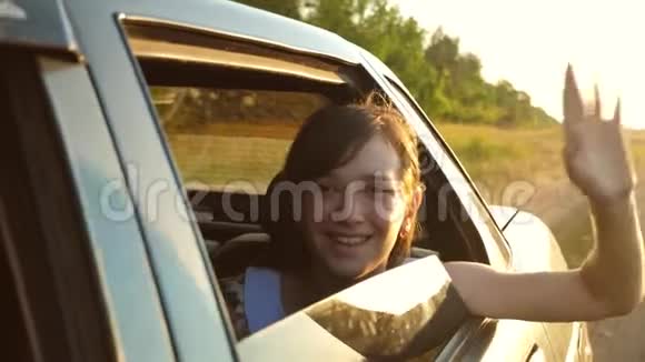 美丽的长发女孩骑着一辆车双手放在窗前微笑着挥动着她的手怒视着视频的预览图