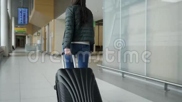 旅行者女性正在现代机场候机楼步行携带手提箱后景视频的预览图