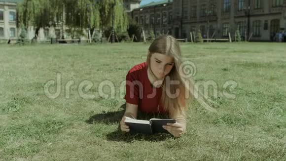 美丽的女孩在校园草坪上看书视频的预览图