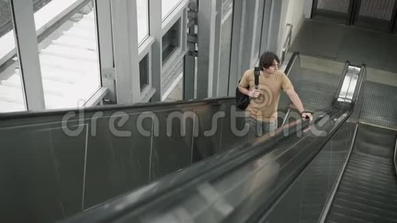 坐在自动扶梯上的一个健壮的年轻人视频的预览图