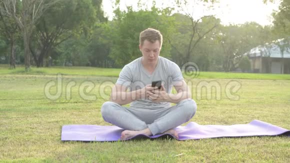快乐的年轻帅哥坐在公园里打电话视频的预览图