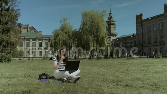 在草坪上做笔记本电脑的漂亮女生视频的预览图