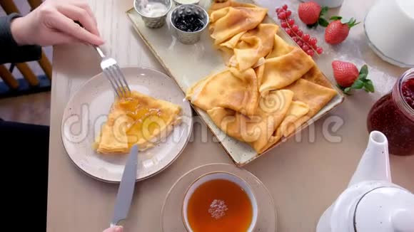 女人正在吃俄罗斯传统的薄煎饼在盘子里放上果酱酸奶油和草莓而且视频的预览图