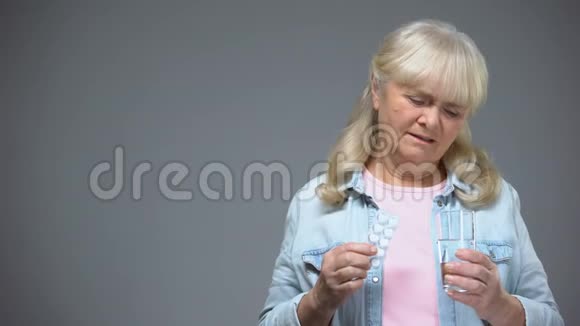 不高兴的老太太拿着不愿服用的药丸无效的药物视频的预览图