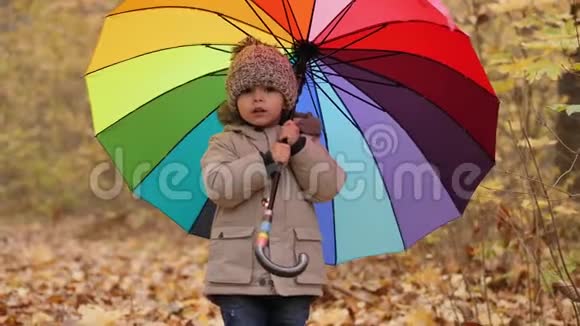 微笑的小男孩拿着一把五颜六色的大伞视频的预览图