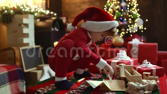 戴圣诞帽的快乐可爱的孩子带着礼物过圣诞节孩子在室内圣诞树附近玩快乐的孩子视频的预览图