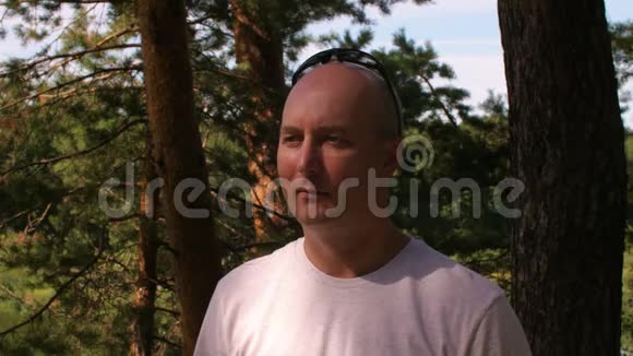 一个严肃的秃顶中年男人在森林中侧视视频的预览图