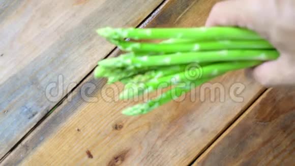 手的慢动作把芦笋蔬菜放在木头上视频的预览图