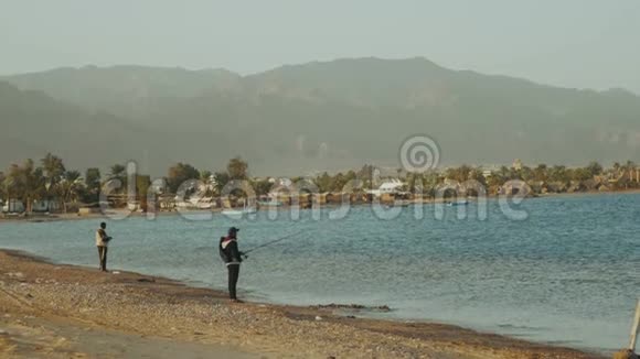 两个渔夫在海上随波逐流从海滩上旋转的人钓鱼动作缓慢视频的预览图