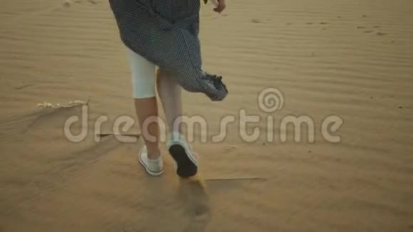 美丽的年轻女子在沙漠中日落时散步的剪影女性穿越沙漠沙丘特写慢镜头视频的预览图