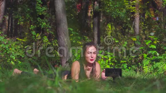 美丽的年轻黑发女子拍摄锻炼过程视频为她的博客显示拇指在公园与智能手机视频的预览图