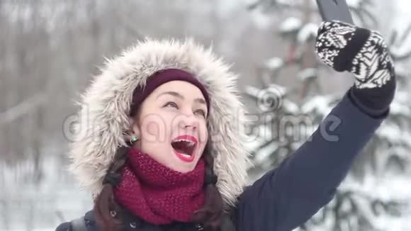 年轻漂亮的女孩在冬天的公园里散步时在智能手机上自拍视频的预览图