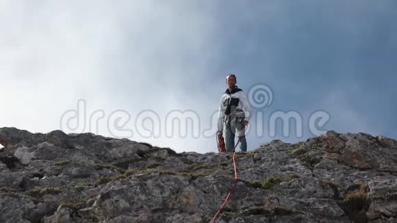 登山者站在山顶时动作缓慢抛出一根绳子视频的预览图