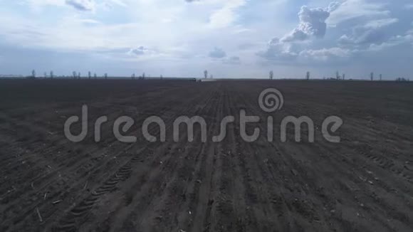 在犁耕的棕壤和美丽的天空上农业机械在犁田上的无人视野视频的预览图