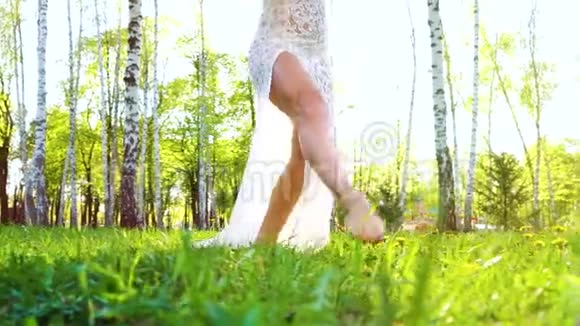 低角度拍摄的女子腿赤脚在绿色草地上跳舞镜头耀斑视频的预览图