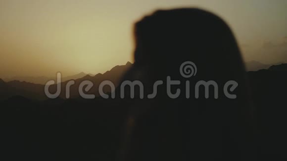 美丽的年轻女子在沙漠中日落时散步的剪影女性穿越沙漠沙丘特写慢镜头视频的预览图