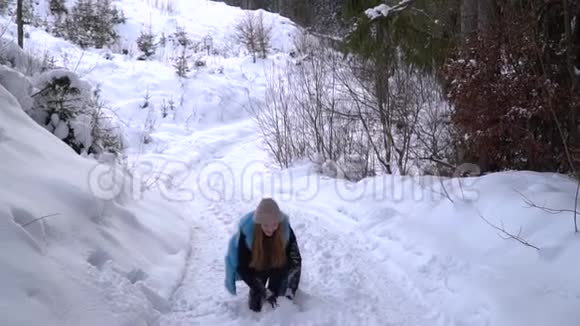 年轻漂亮的女孩在冬天的森林里玩她高兴地扔雪和弹跳女孩很快乐视频的预览图