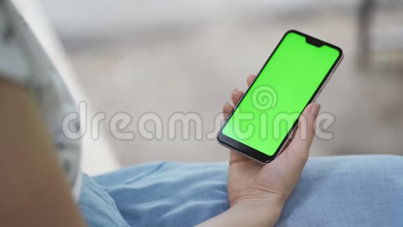 漂亮的女孩手里拿着一个绿色屏幕的智能手机视频的预览图