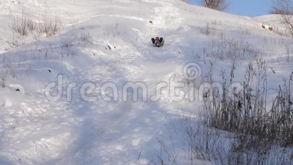 快乐的女孩在雪中滑下山冬天在圣诞公园玩的女孩慢动作视频的预览图