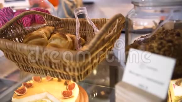 在无花果芝士蛋糕附近的面包店里有法国糕点的Wicker篮子站在玻璃显示器上食品概念艺术视频的预览图