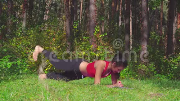 年轻的黑发女人在阳光明媚的森林里做运动里面和谐健康的生活方式视频的预览图
