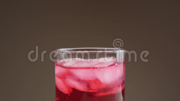 冰块落在杯子里用红色苏打水溅起水花和气泡视频的预览图