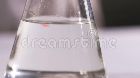 在实验室里一位科学家进行化学实验将红色液体倒入烧瓶中概念生化视频的预览图