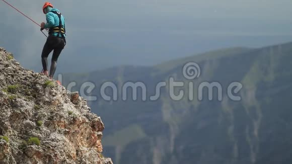 登山者轻轻地下降到悬崖的边缘视频的预览图