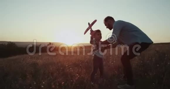 日落时分爸爸和他的儿子一起玩飞机一起度过美好的时光视频的预览图