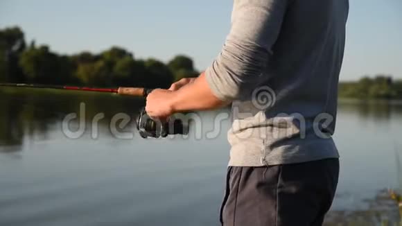 渔夫的手在鱼竿上扭动鱼线圈视频的预览图