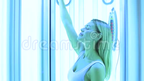 一个身材苗条的女孩在现代垂直日光浴室里日光浴的特写镜头视频的预览图