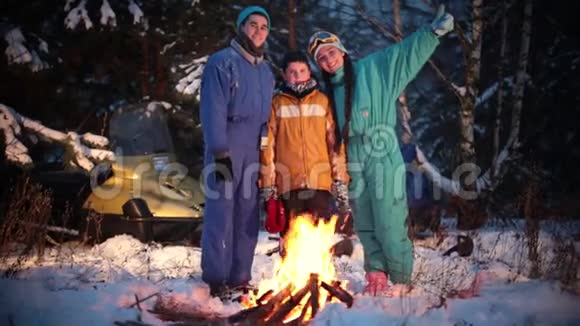 冬季森林一家人在火边的树林里拍照在镜头里看视频的预览图