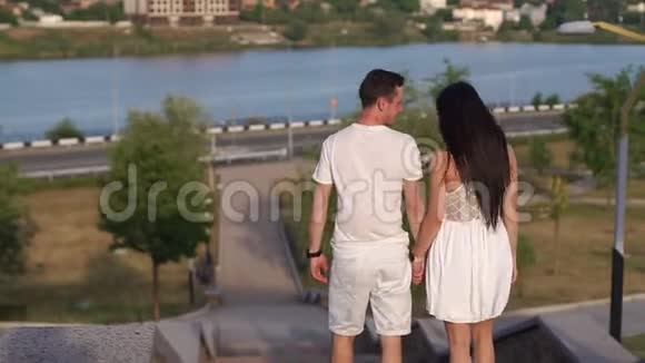 一对相爱的夫妇在日落时分走下楼梯在公园里散步慢点视频的预览图
