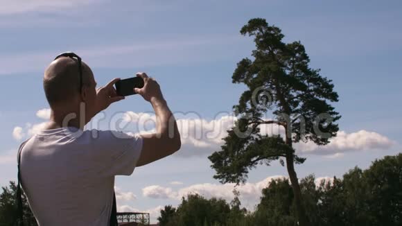 大自然中在智能手机上拍摄松树照片或录像的成年男子视频的预览图