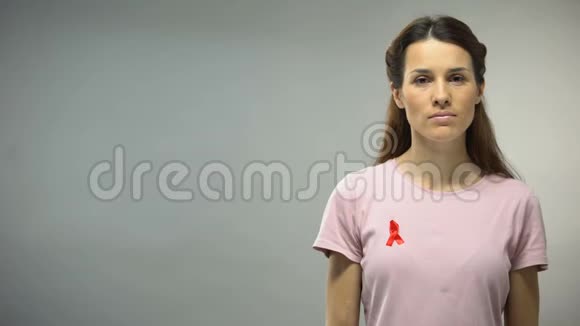 穿着红色缎带的年轻女子在镜头前看着艾滋病毒艾滋病宣传标志视频的预览图