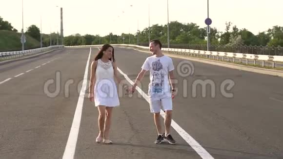 恋爱中的青少年牵着手走在空荡荡的夏日路上慢动作视频的预览图