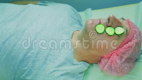 一个戴着手套的美容师女人的手从男人脸上取出黄瓜片视频的预览图