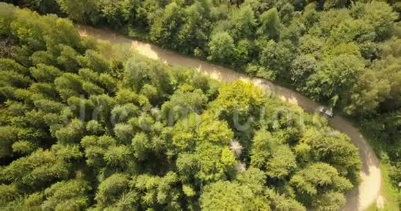 在森林和山脉的乡村道路上驾驶汽车的鸟瞰图视频的预览图